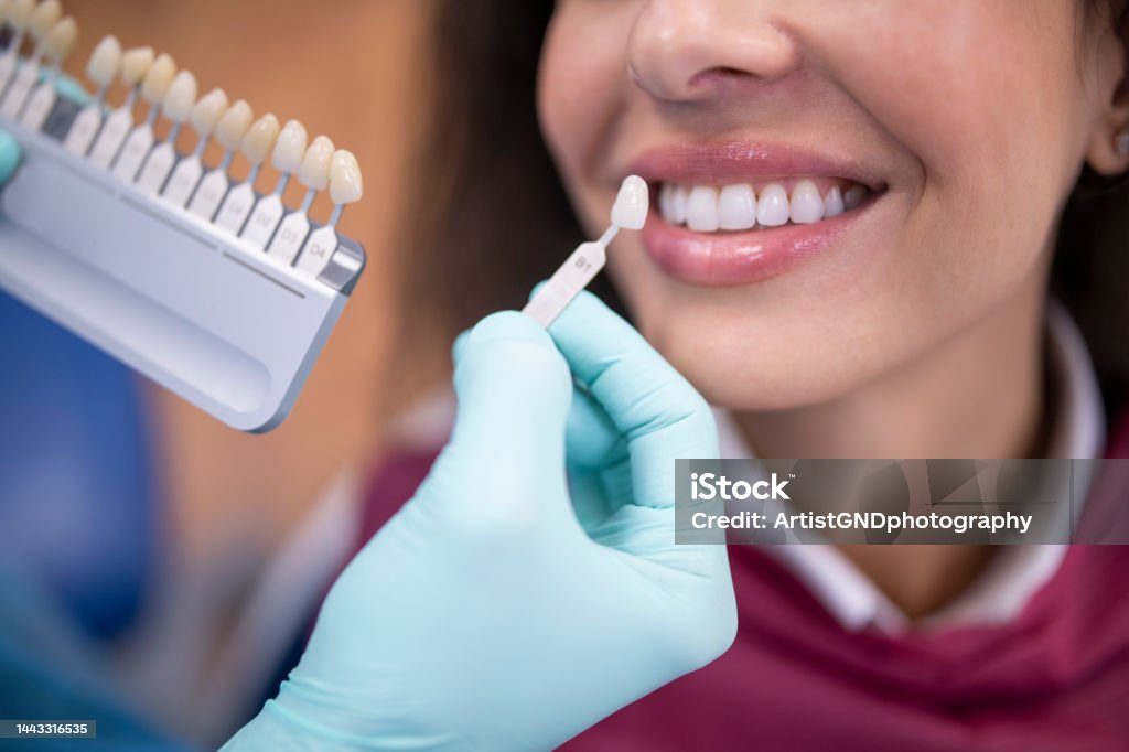 Dentist uses a palette tooth color sample to determine shade of patient's teeth.